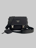 A black Prada shoulder bag with a matching zippered pouch and a wide black Burberry strap, displayed on a clean white reflective surface.